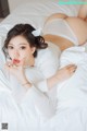 A woman laying on top of a bed wearing a white sweater.